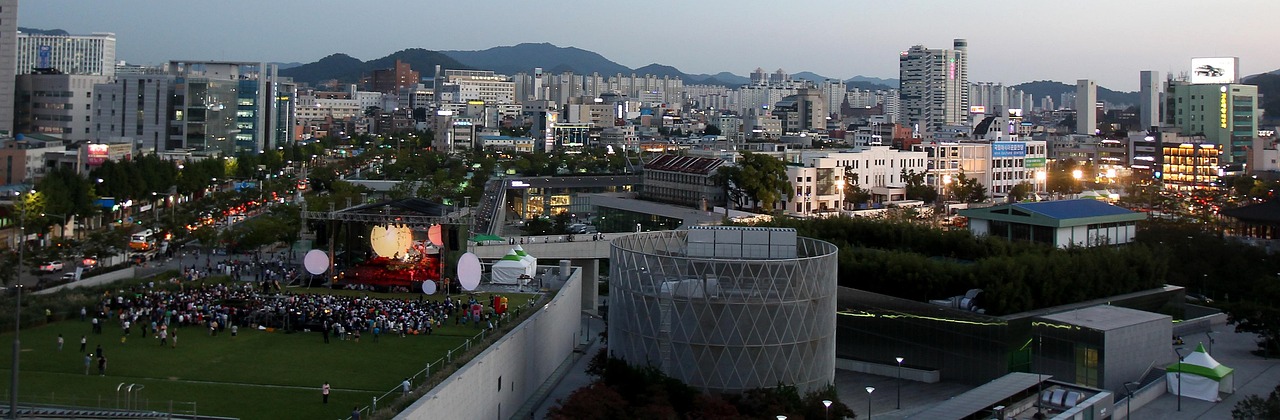 An audience gathered on a city lawn for an outdoor concert at dusk