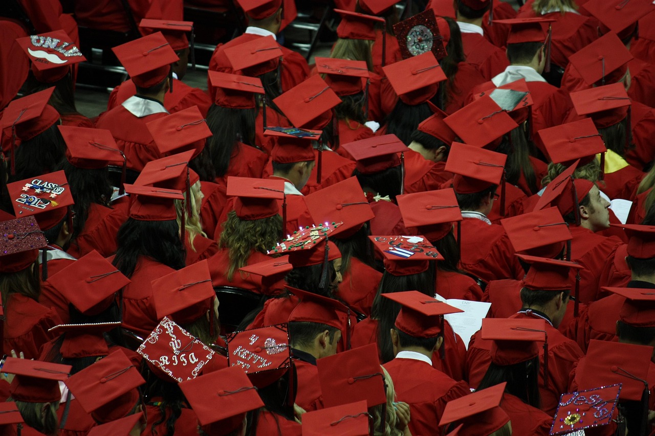 Rows of graduates wearing red caps and gowns during a graduation ceremony