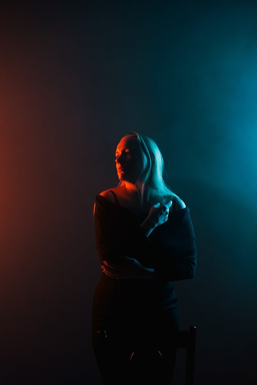 A woman in red and blue studio lighting against a dark background