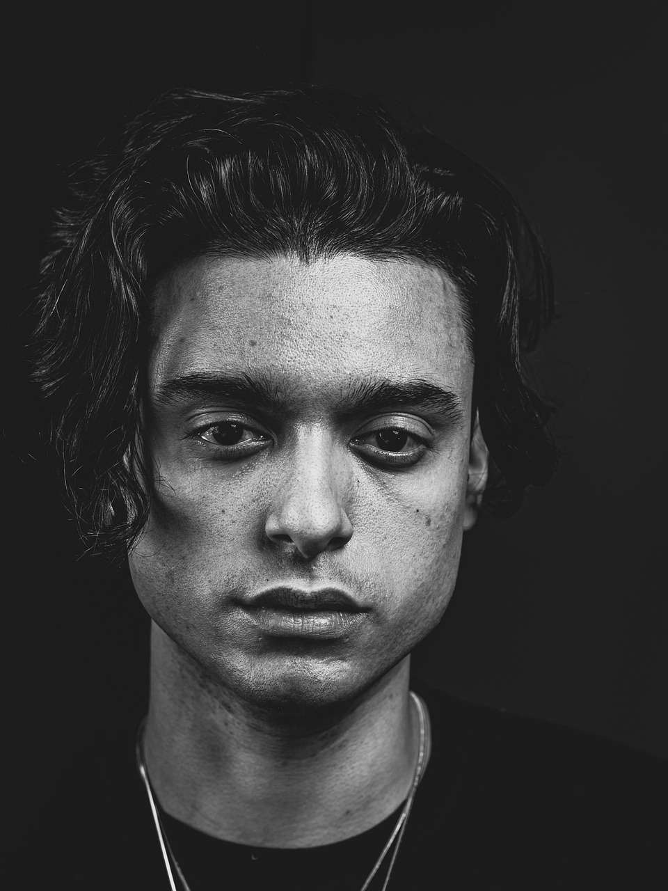 A young man's face in a dramatic black and white studio portrait