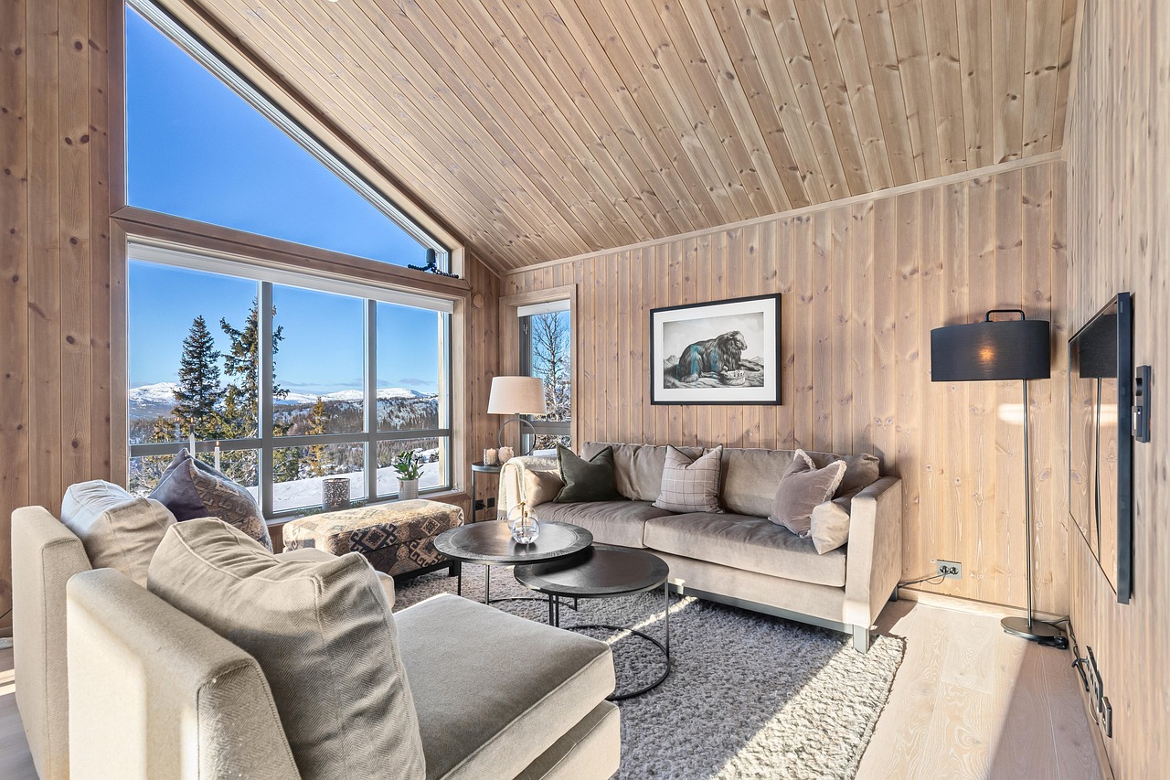 A bright living room with timber walls, a vaulted ceiling, gray seating and large windows
