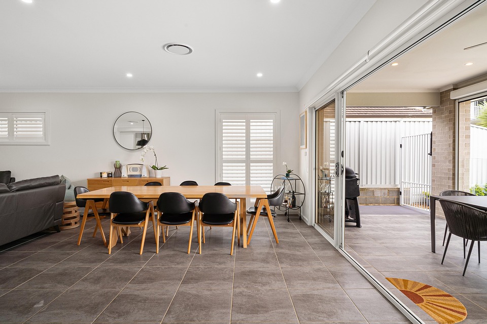 An open dining room with a wooden table and sliding glass doors leading to a patio
