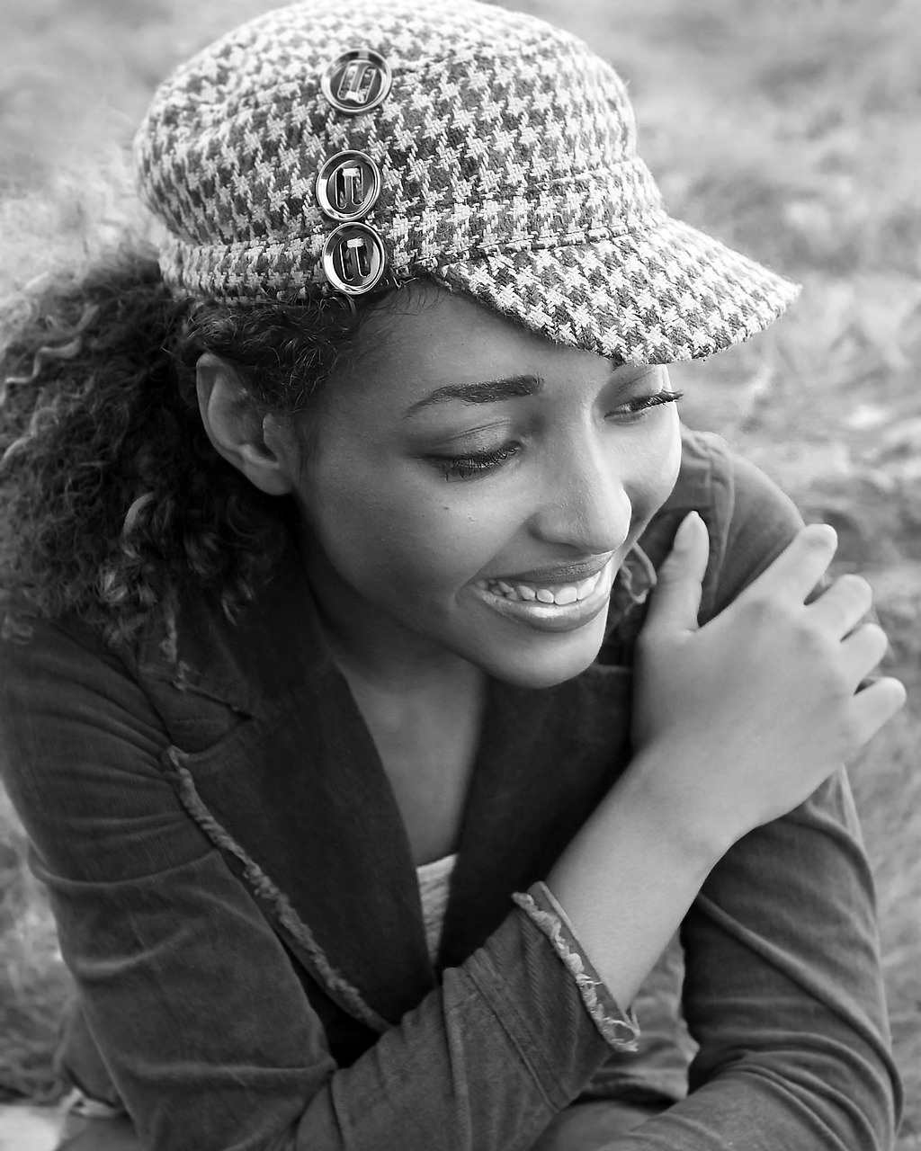 A young woman wearing a patterned cap in a relaxed outdoor portrait