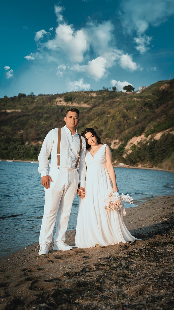 A newlywed couple holding hands beside the sea