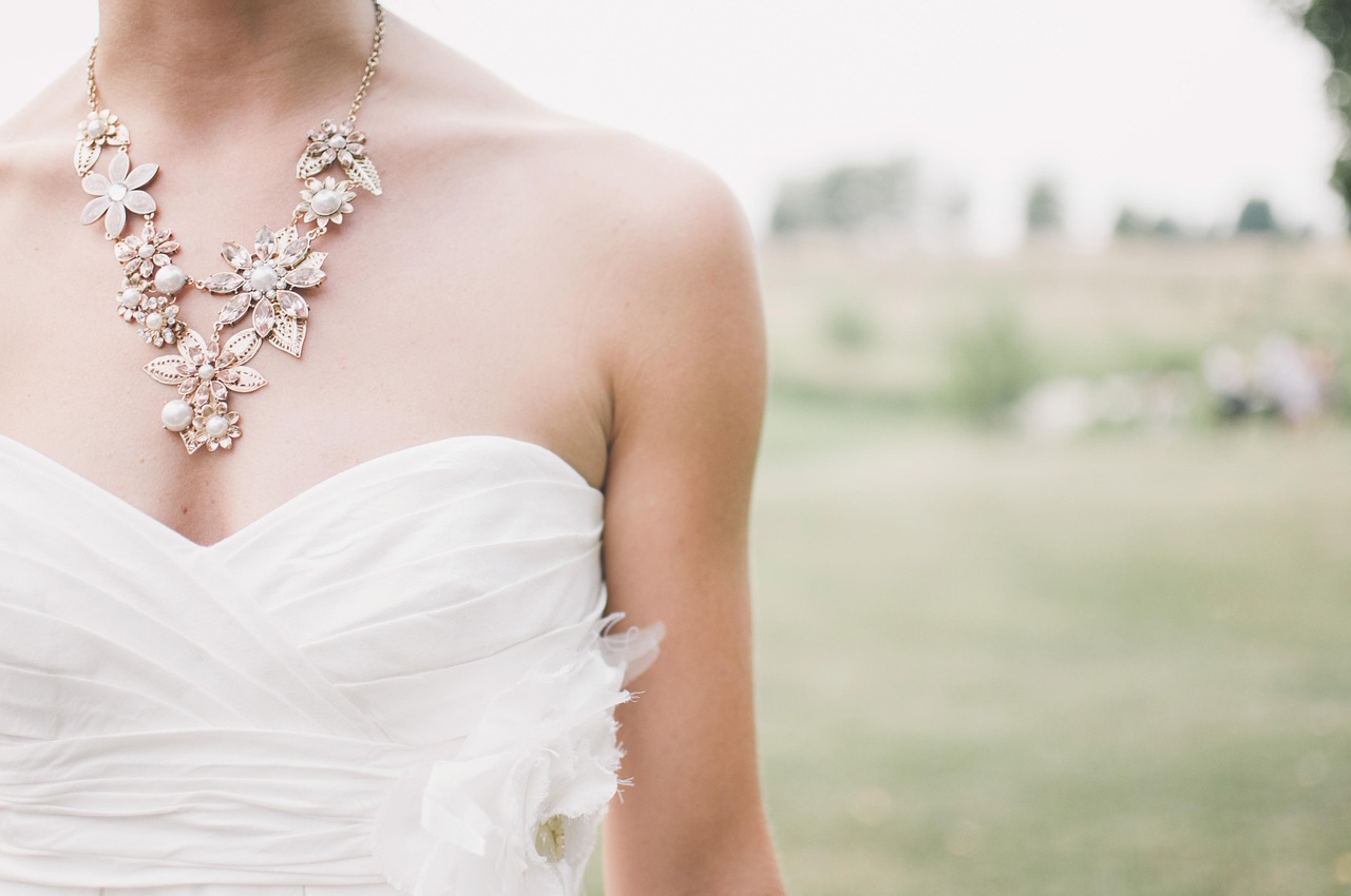 A white bridal gown and floral necklace photographed in soft daylight