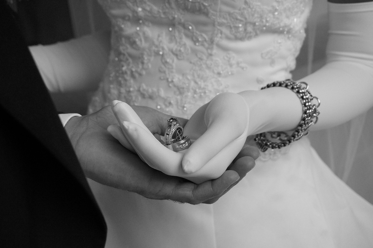 Close-up of a couple's hands and wedding rings in black and white